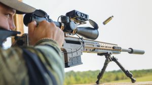 A shooter firing a suppressed Barrett MRAD precision rifle from a bipod