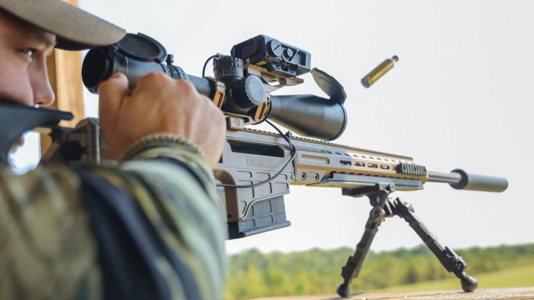 A shooter firing a suppressed Barrett MRAD precision rifle from a bipod