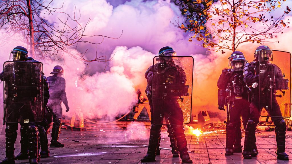 French public-order officers behind riot shields in coloured smoke