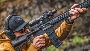 A shooter aiming a semi-automatic rifle fitted with a low-power variable optic