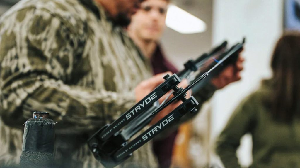 A customer examining a compound bow in an archery shop