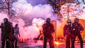 French public-order officers behind riot shields in coloured smoke