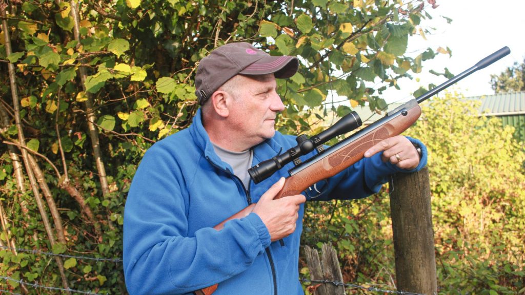 Pete Evans shouldering the Weihrauch HW30S break-barrel air rifle beside a hedgerow